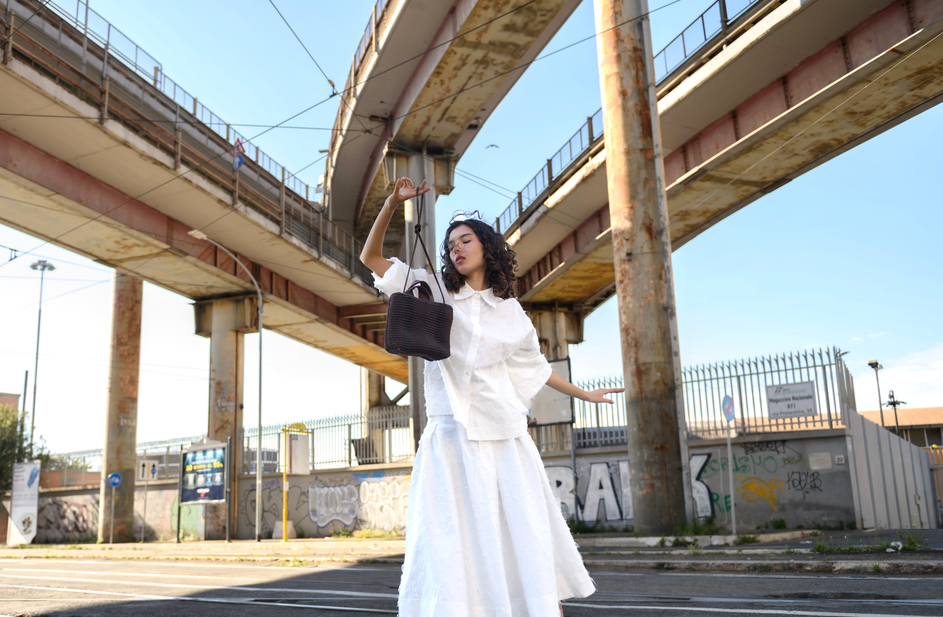 Woman holding handmade leather bag
by Fausto Santini under an urban bridge